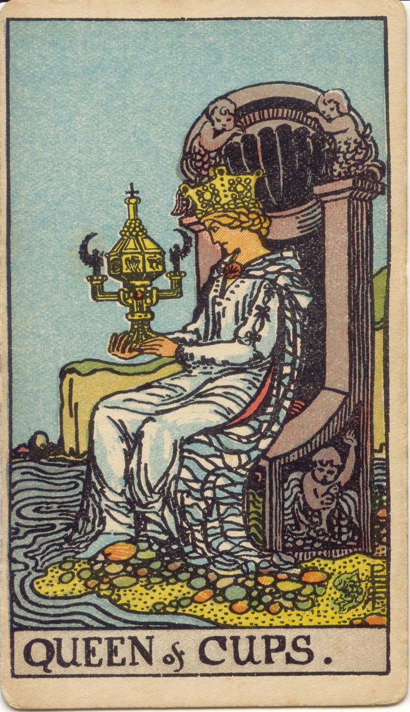 Карта Таро Королева Кубков, 1909 год: королева на троне у кромки моря пристально смотрит на закрытый узорный золотой кубок