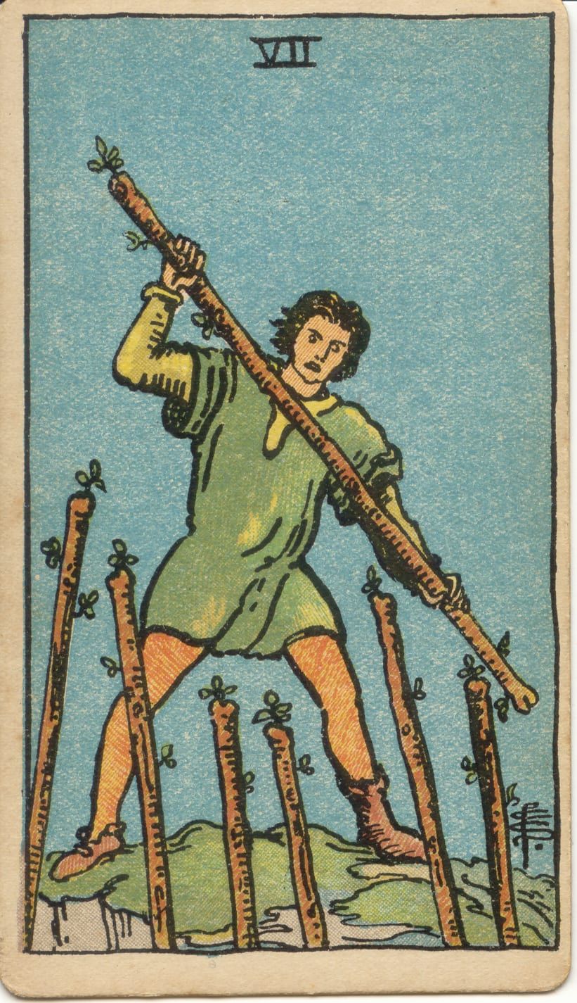 Карта Таро Семёрка Жезлов, 1909 год: юноша в зелёной тунике на вершине холма отбивается жезлом от шести жезлов снизу